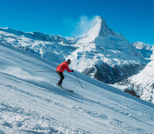 A skiier in motion on a steep slope in the mountains on a beautiful day