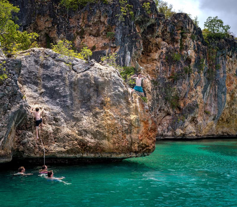 A family swimming and jumping off rocks on a luxury travel vacation