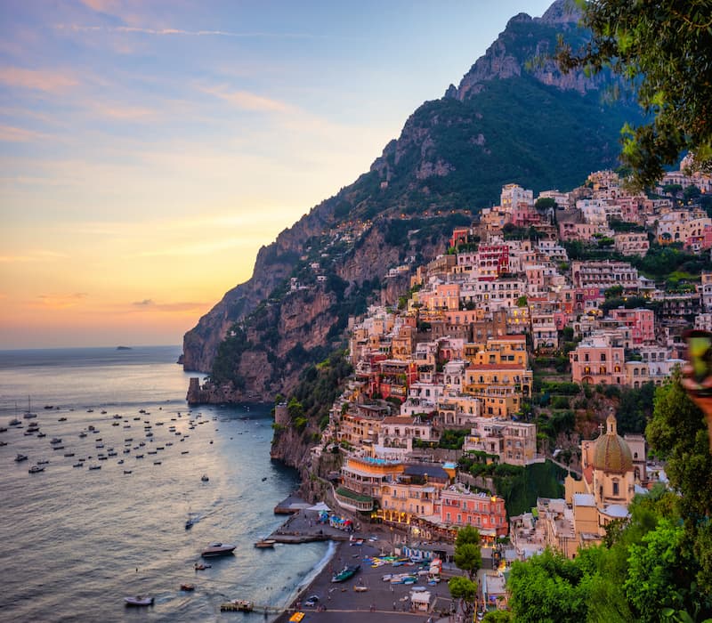 Sunset behind a cliffside Italian village, a major focus of many bespoke luxury itineraries in Italy