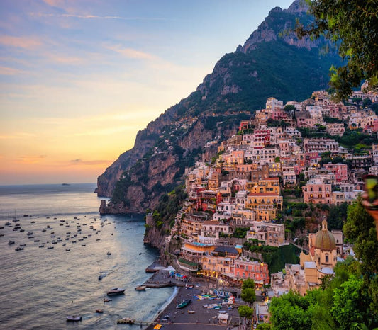 Sunset behind a cliffside Italian village, a major focus of many bespoke luxury itineraries in Italy